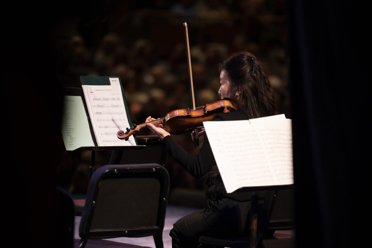 A violinist playing on stage in front of sheet music.