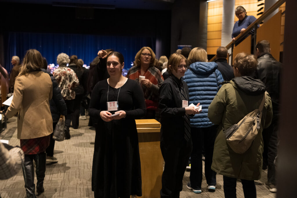 People enter the Holiday Pops Concert and receive a schedule of the concert.