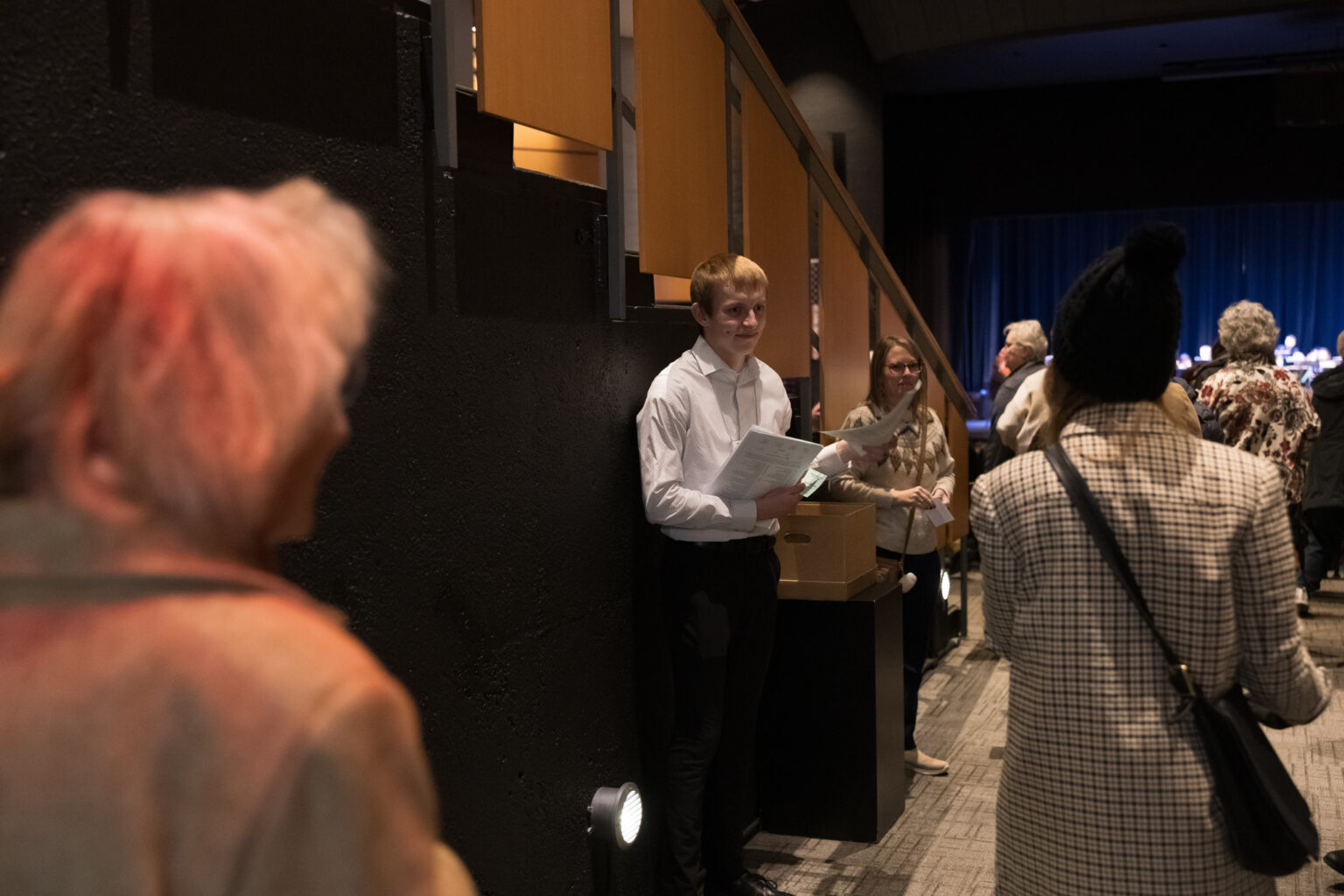 People enter the Holiday Pops Concert and receive a schedule of the concert.